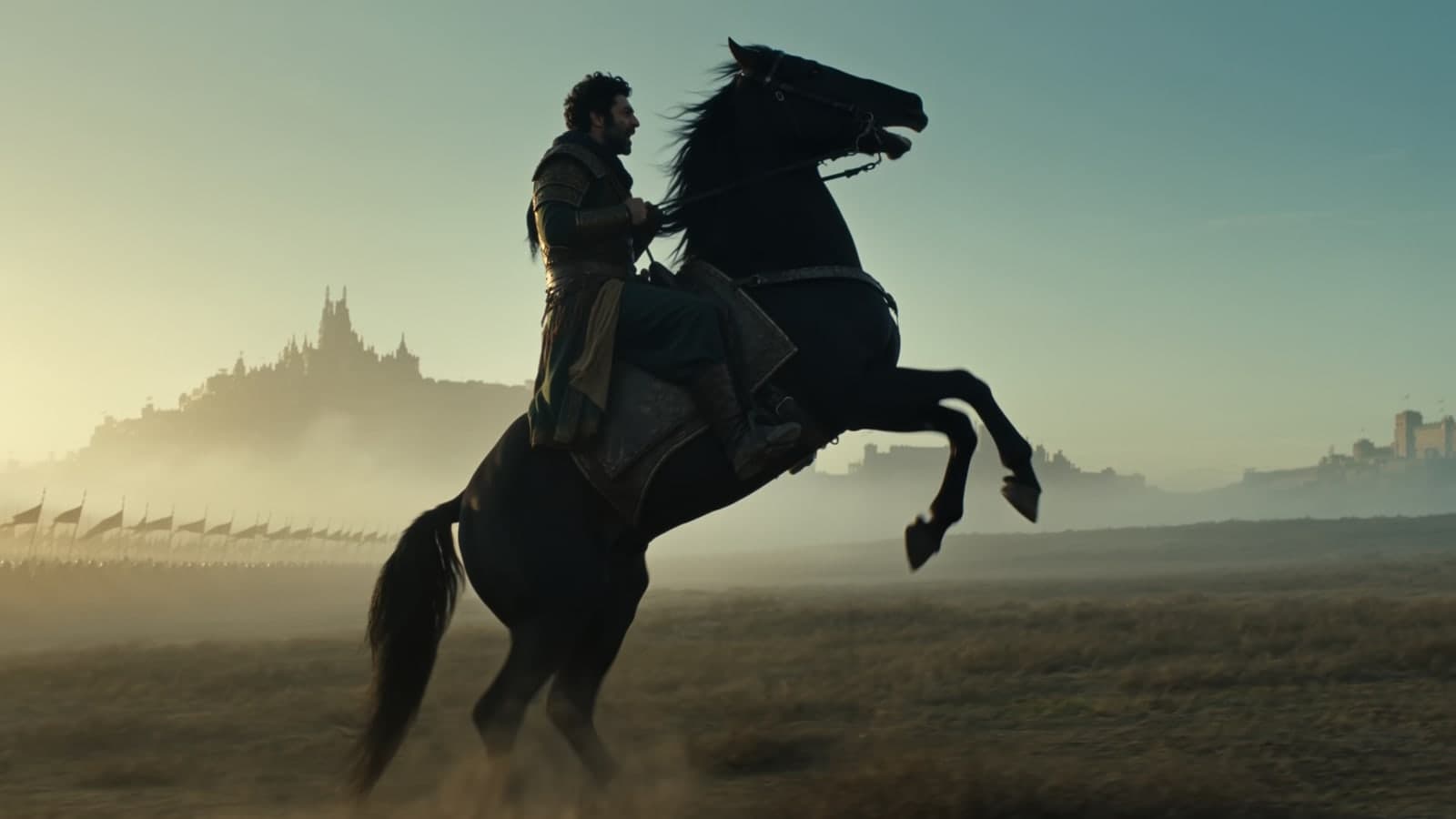 A rider on a rearing horse at dawn, banners and a hilltop fortress behind him, in A True Warrior