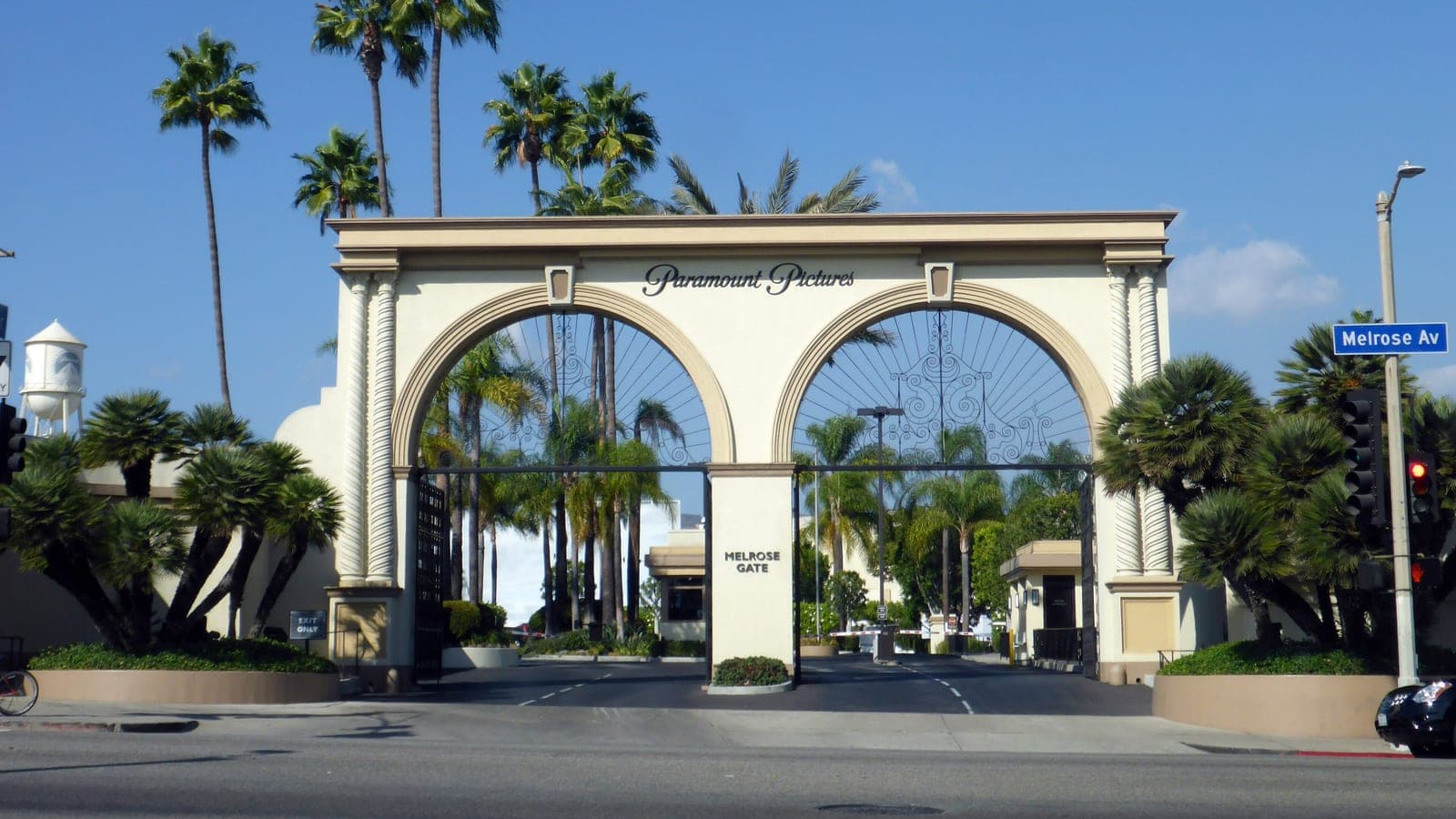 The arched Melrose Gate entrance to the Paramount Pictures lot in Hollywood, with palm trees and the studio's water tower behind it.